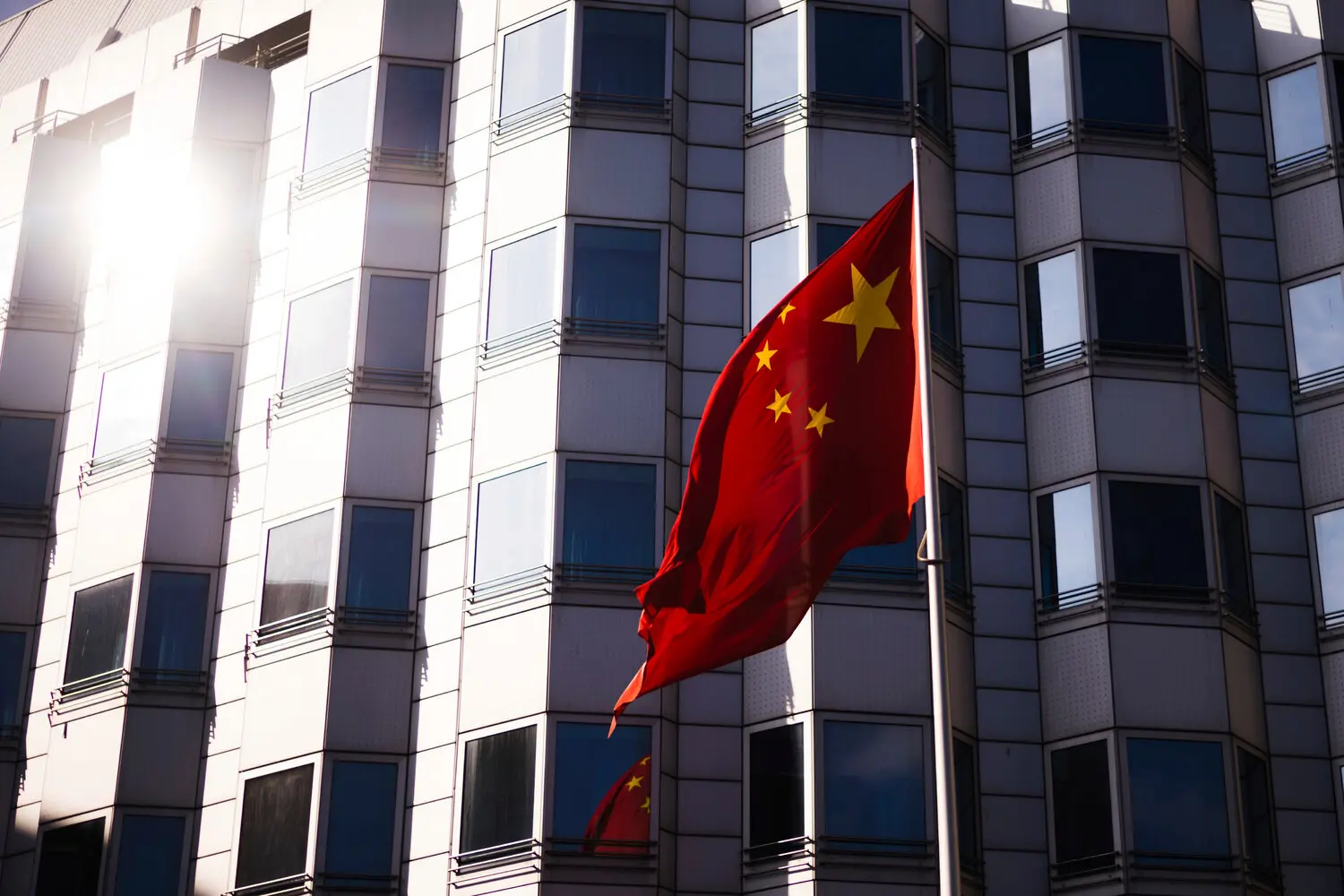 A Chinese flag in front of a modern gray building.