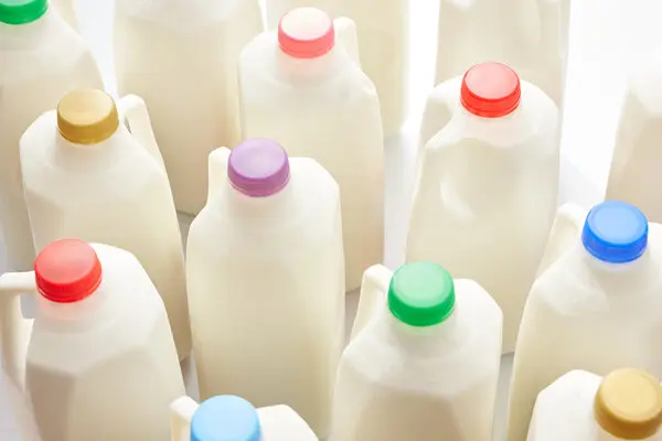 A group of plastic milk cartons with different colored caps.